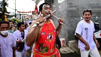 Seorang pemuja kuil Kuan Tae Kun menusuk pipinya dengan pedang saat mengikuti prosesi selama Festival Vegetarian tahunan di Phuket, Thailand, Rabu (28/9/2022).  