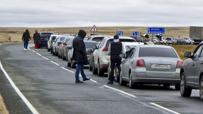Tak Mau Dikirim ke Ukraina, Warga Rusia Kabur ke Kazakhstan People walk next to their cars queuing to cross the border into Kazakhstan at the Mariinsky border crossing, about 400 kilometers (250 miles) south of Chelyabinsk, Russia, Tuesday, Sept. 27, 2022. Officials say about 98,000 Russians have crossed into Kazakhstan in the week since President Vladimir Putin announced a partial mobilization of reservists to fight in Ukraine. (AP Photo)