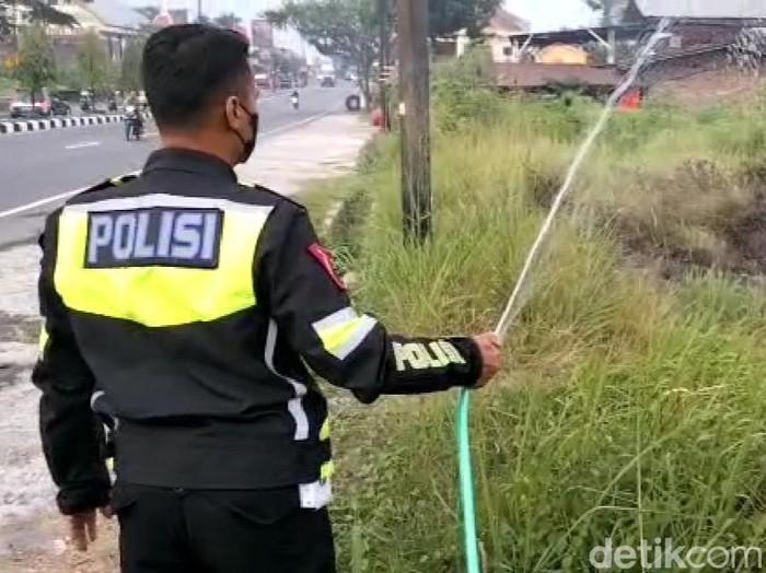 Aipda Heru Suryanto memadamkan api dengan selang seadanya di tepi jalan Jogja-Solo, Kamis (29/9/2022) sore.