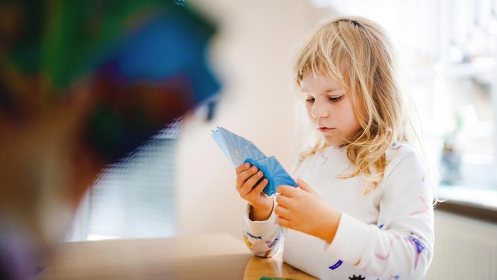 Adorable cute toddler girl playing picture card game. Happy healthy child training memory, thinking. Creative indoors leisure and education of kid during pandemic coronavirus covid quarantine disease.