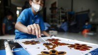 Seorang anak sedang menyelesaikan pembuatan batik.