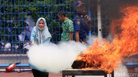 Seorang guru berusaha memadamkan api dengan hydrant.