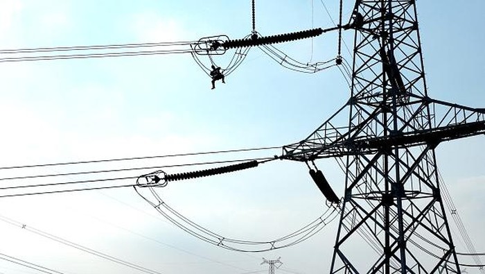 LIANYUNGANG, CHINA - SEPTEMBER 28: An electrician carries out maintenance work on electric wires of a 500KV transmission line project at sunset on September 28, 2022 in Lianyungang, Jiangsu Province of China. (Photo by Geng Yuhe/VCG via Getty Images)