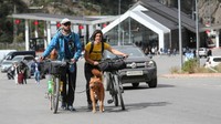 Pelancong dengan anjing mendorong sepeda setelah melintasi perbatasan dengan Rusia di pos pemeriksaan perbatasan Verkhny Lars - Zemo Larsi, Georgia, Rabu, (28/9/2022). (REUTERS/Irakli Gedenidze)