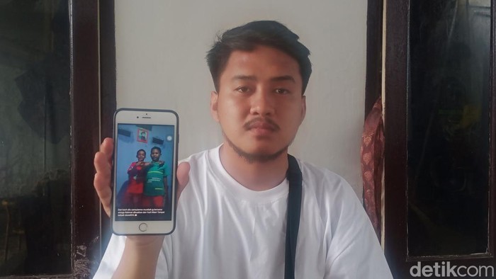 Wawan saat menunjukkan foto adiknya yang tewas kecelakaan karena dikejar OTK pakai busur panah di Makassar.