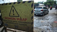 Jalan yang rusak ini telah ditandai plang Mohon Maaf Perjalanan Anda Terganggu Ada Pengerjaan Sungai. Dua buah plang tersebut diletakkan tepat di jalan yang rusak.