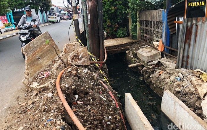 Duh, Sudah 2 Bulan Proyek Got di Tangsel Masih Berantakan Warga melintas di samping proyek galian parit di Jl Pondok Betung Raya, Pondok Aren, Tangerang Selatan, Jumat (30/9/2022). Proyek galian drainase tersebut sudah berlangsung hampir dua bulan, tepatnya akhir Juli lalu, namun belum tuntas sampai hari ini. Material gorong-gorong maupun beton U-ditch masih berserakan di pinggir jalan. Terdapat sisa lumpur galian yang cukup membahayakan karena membuat penyempitan jalan. Selain itu, ceceran lumpur membuat jalanan licin saat hujan tiba. Warga berharap proyek ini segera tuntas.