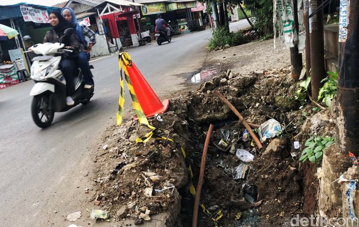 Duh, Sudah 2 Bulan Proyek Got di Tangsel Masih Berantakan Warga melintas di samping proyek galian parit di Jl Pondok Betung Raya, Pondok Aren, Tangerang Selatan, Jumat (30/9/2022). Proyek galian drainase tersebut sudah berlangsung hampir dua bulan, tepatnya akhir Juli lalu, namun belum tuntas sampai hari ini. Material gorong-gorong maupun beton U-ditch masih berserakan di pinggir jalan. Terdapat sisa lumpur galian yang cukup membahayakan karena membuat penyempitan jalan. Selain itu, ceceran lumpur membuat jalanan licin saat hujan tiba. Warga berharap proyek ini segera tuntas.