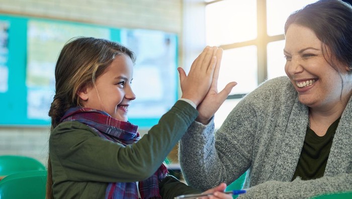 Shot of an elementary school girl high fiving her teacher in class