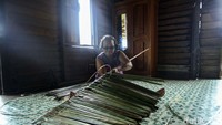 Seorang warga tampak sibuk membuat anyaman di dalam rumahnya.