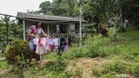 Seorang warga menjemur pakaian di halaman rumahnya.