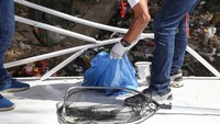 Relawan mengumpulkan sampah ke dalam kantong plastik.