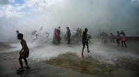 Anak-anak bermain dengan ombak di Malecon, Havana, Kuba, Kamis (29/9/2022) waktu setempat.  