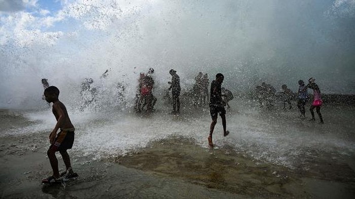 Ombak Besar Jadi Wisata Anak-anak di Kuba Children play with the waves at the Malecon in Havana, on September 29, 2022, in the aftermath of Hurricane Ian. - Authorities were slowly restoring electricity in Cuba following a power outage in the country caused by Hurricane Ian, which killed two people and left widespread damage. (Photo by YAMIL LAGE / AFP) (Photo by YAMIL LAGE/AFP via Getty Images)