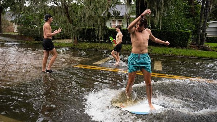 Warga Florida Asik Main Selancar di Tengah Banjir Boys skim board on a flooded street in the aftermath of Hurricane Ian in Orlando, Florida on September 29, 2022. - Hurricane Ian left much of coastal southwest Florida in darkness early on Thursday, bringing