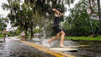 Banjir yang belum menyusut dimanfaatkan sejumlah warga untuk bermain selancar.  