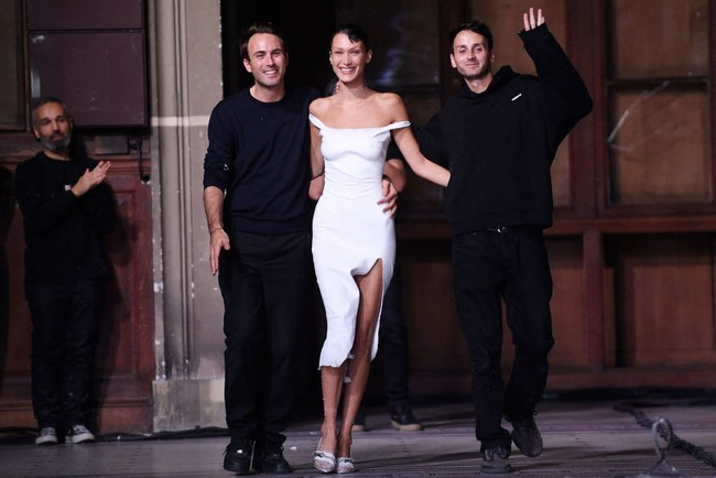 Bella Hadid tampil bersama desainer Coperni, Sebastien Meyer dan Arnaud Vaillant. “Sudah menjadi tugas kami sebagai desainer untuk mencoba hal baru dan menunjukkan apa yang mungkin di masa depan. Kami tidak akan mencari untung dari ini, tapi ini adalah momen yang indah, pengalaman yang menciptakan emosi,” katanya. Foto: Dok. Getty Images.