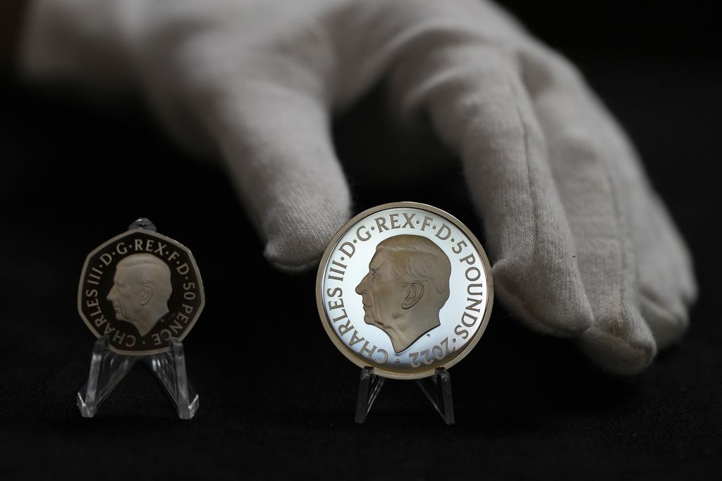 Britain Royals Two new coins bearing official coinage portrait of King Charles III, on the left is the new 50 pence coin, and right is the new 5 pound commemorative coin, which will be among the first coins to bear the new king's head, during a press preview in London, Thursday, Sept. 29, 2022. The likeness of the king was created by British sculptor Martin Jennings, and approved by the king. (AP Photo/Alastair Grant)