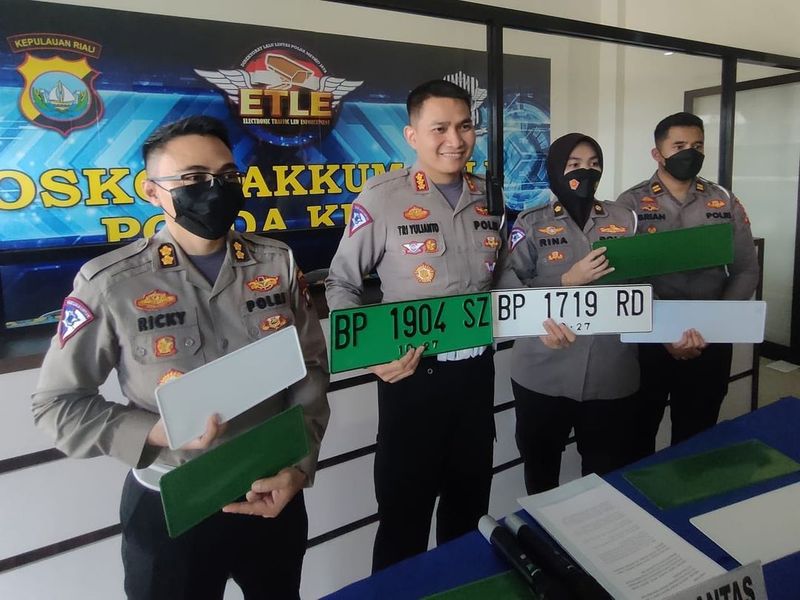 Pelat nomor kendaraan berwarna hijau.