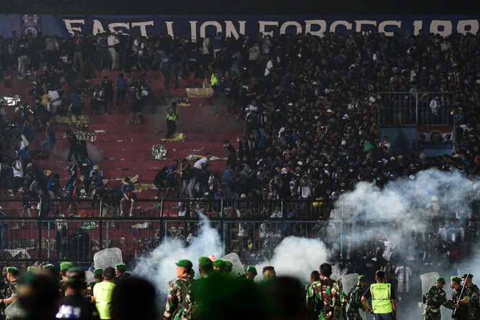 This picture taken on October 1, 2022 shows security personnel (lower) on the pitch after a football match between Arema FC and Persebaya Surabaya at Kanjuruhan stadium in Malang, East Java. - At least 127 people died at a football stadium in Indonesia late on October 1 when fans invaded the pitch and police responded with tear gas, triggering a stampede, officials said. (Photo by AFP) (Photo by STR/AFP via Getty Images)