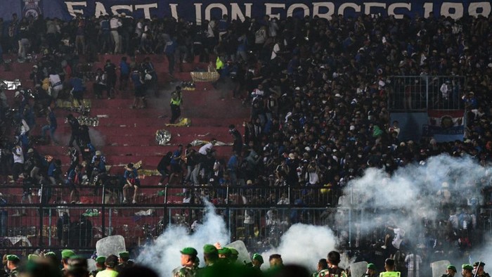 This picture taken on October 1, 2022 shows security personnel (lower) on the pitch after a football match between Arema FC and Persebaya Surabaya at Kanjuruhan stadium in Malang, East Java. - At least 127 people died at a football stadium in Indonesia late on October 1 when fans invaded the pitch and police responded with tear gas, triggering a stampede, officials said. (Photo by AFP) (Photo by STR/AFP via Getty Images)