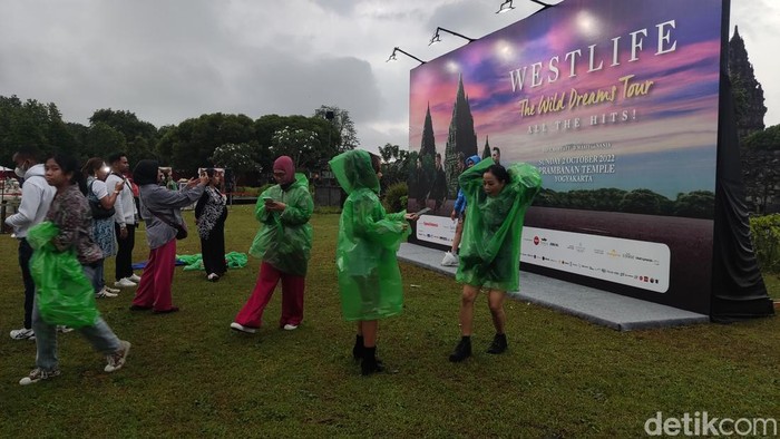 Penonton berfoto di tengah gerimis