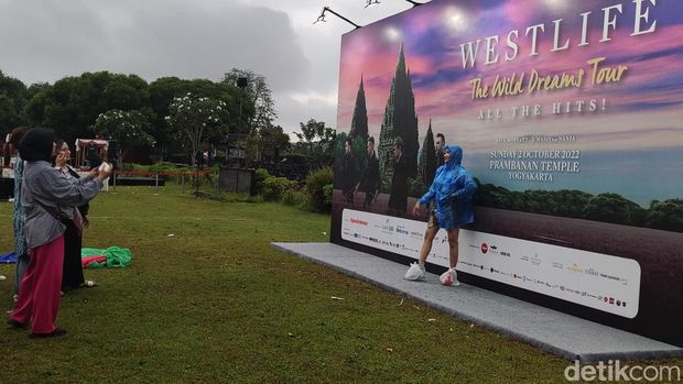 Penonton berfoto di tengah gerimis