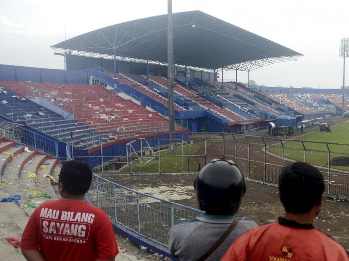 People examine the damage following a soccer match stampede at the Kanjuruhan Stadium in Malang, East Java, Indonesia, Sunday, Oct. 2, 2022. Panic at an Indonesian soccer match after police fired tear gas to to disperse supporters invading the pitch left over 100 people dead, mostly trampled to death, police said Sunday. (AP Photo/Hendra Permana)