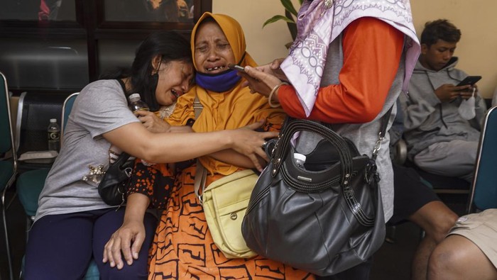 Women weep after receiving confirmation that their family member is among those killed in a soccer riots, at a hospital in Malang, East Java, Indonesia, Sunday, Oct. 2, 2022. Panic at an Indonesian soccer match Saturday left over 150 people dead, most of whom were trampled to death after police fired tear gas to dispel the riots. (AP Photo/Dicky Bisinglasi)