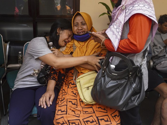 Women weep after receiving confirmation that their family member is among those killed in a soccer riots, at a hospital in Malang, East Java, Indonesia, Sunday, Oct. 2, 2022. Panic at an Indonesian soccer match Saturday left over 150 people dead, most of whom were trampled to death after police fired tear gas to dispel the riots. (AP Photo/Dicky Bisinglasi)