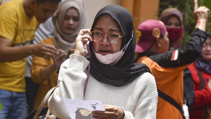 Women weep after receiving confirmation that their family member is among those killed in a soccer riots, at a hospital in Malang, East Java, Indonesia, Sunday, Oct. 2, 2022. Panic at an Indonesian soccer match Saturday left over 150 people dead, most of whom were trampled to death after police fired tear gas to dispel the riots. (AP Photo/Dicky Bisinglasi)