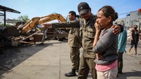 Petugas Satpol PP berusaha menenangkan warga terdampak penertiban bangunan liar tersebut.