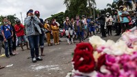 Warga nampak berkumpul di patung singa di luar Stadion Kanjuruhan untuk memberikan ungkapan belasungkawa dan menabur bunga.