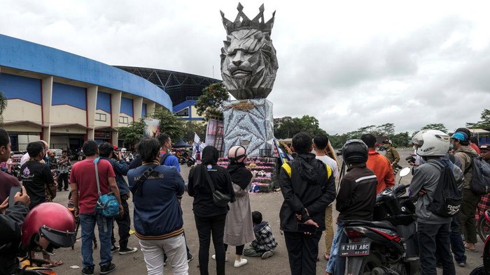 Aksi Warga Tabur Bunga di Patung Singa Kanjuruhan MALANG, INDONESIA - OCTOBER 03: Supporters and people lay flowers as they pay condolence to the victims outside Kanjuruhan Stadium on October 03, 2022 in Malang, Indonesia. A riot and stampede broke out at a football stadium in East Java on Saturday. Police fired tear gas to disperse fans who had invaded the pitch after and began fighting the match ended. A stampede for the exits has resulted in at least 125, media reports said, with many still injured in hospitals. (Photo by Ulet Ifansasti/Getty Images)