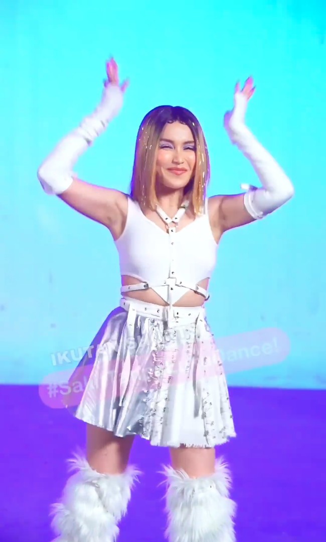 Dalam unggahan Ayu mengenakan outfit yang didominasi oleh warna putih. Ia memadukan atasan crop top tak berlengan dengan rok pendek berwarna silver. Penampilannya itu kemudian dilengkapi dengan sepasang sarung tangan berwarna putih yang panjangnya sampai ke lengan dan sepatu bulu yang cukup tinggi hingga di atas dengkul. Foto: Instagram/@ayutingting92