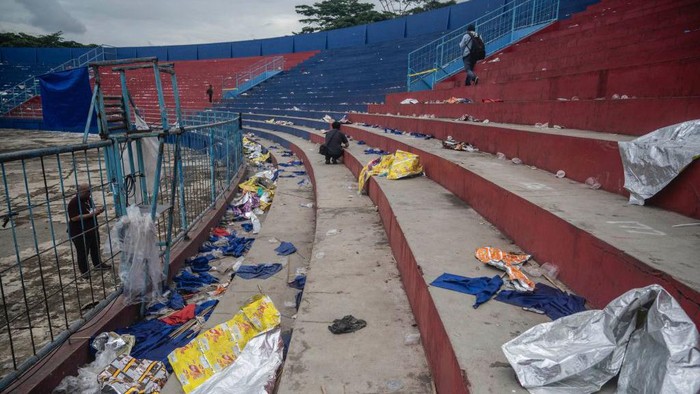 TOPSHOT - People walk amongst debris in the stands at Kanjuruhan stadium days after a deadly stampede following a football match in Malang, East Java on October 3, 2022. - Anger against police mounted in Indonesia on October 3 after at least 125 people were killed in one of the deadliest disasters in the history of football, when officers fired tear gas in a packed stadium, triggering a stampede. (Photo by Juni Kriswanto / AFP) (Photo by JUNI KRISWANTO/AFP via Getty Images)
