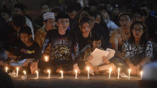 Warga bersama suporter Arema FC (Aremania) berdoa bersama di halaman Stadion Kanjuruhan, Malang, jawa Timur, Minggu (2/10/2022). Aksi doa bersama tersebut untuk mendoakan korban yang meninggal dunia dalam peristiwa itu. ANTARA FOTO/Zabur Karuru/nym.