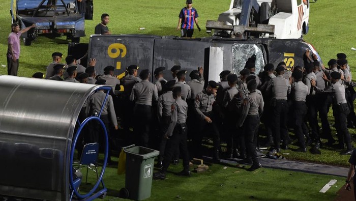 Polisi mengevakuasi mobil yang rusak akibat kerusuhan di lapangan Stadion Kanjuruhan, Malang, Jawa Timur, Minggu (2/10/2022). Kerusuhan yang terjadi di stadion tersebut menyebabkan 13 unit mobil rusak, 10 unit diantaranya mobil polisi dan tiga unit mobil pribadi. ANTARA FOTO/Zabur Karuru/nym.