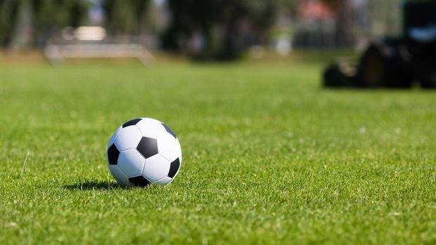 Black and white soccer ball on green soccer pitch.
