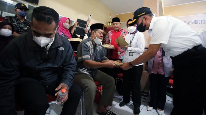 Keluarga Korban Tragedi Kanjuruhan Dapat BLT + Sembako Menko PMK Muhadjir Effendi (kanan) menyerahkan bansos kepada keluarga korban meninggal tragedi Kanjuruhan di Kantor Kecamatan Lowokwaru, Kota Malang, Jawa Timur, Senin (3/10/2022). Mensos Tri Rismaharini bersama Menko PMK Muhadjir Effendi dan Wakil Ketua MPR Ahmad Basarah menyampaikan belasungkawa sekaligus menyerahkan secara langsung bansos berupa uang tunai dan sembako kepada sejumlah keluarga korban tragedi Kanjuruhan di wilayah tersebut. ANTARA FOTO/Irfan Anshori/rwa.