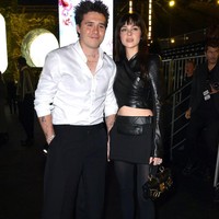 Sebelumnya, pasangan muda itu hadir di fashion show Balmain. Nicola tampil edgy dengan crop top kulit, rok mini dan stocking. Gaya serba hitamnya itu kontras dengan suaminya yang memilih menggunakan kemeja putih.Foto: Getty Images