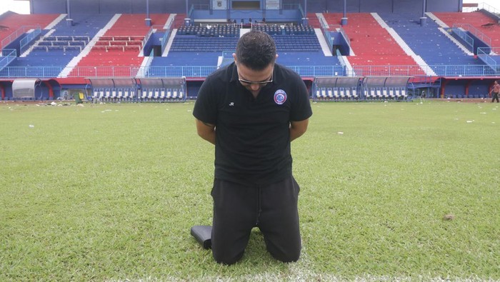 Pelatih Arema FC Javier Roca berlutut di tengah lapangan.