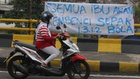 Pengendara motor melintasi spanduk yang menunjukkan keprihatinan atas tragedi kanjuruhan di Jalan Sukarno Hatta, Malang. Spanduk tersebut bertuliskan Semua ibu akan membenci sepak bola. (Antara Foto/Ari Bowo Sucipto)