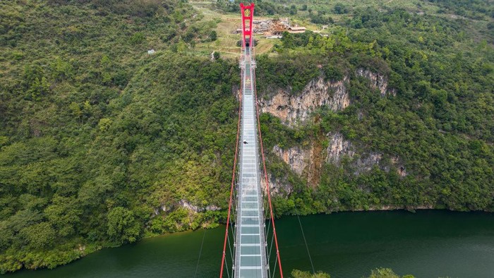 1243565037 QINGYUAN,CHINA - SEPTEMBER 23: An aerial view of the Qingtian Glass Bridge on September 23, 2022 in Qingyuan, Guangdong Province of China.The Qingtian Glass Bridge took three years and cost 300 million yuan to build. It was completed and put into operation in January 2020. With a total length of 526.14 meters, it became the