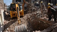 Sebuah mobil excavator menggali reruntuhan bangunan tua yang roboh saat sedang dihancurkan di Gurgaons Udyog Vihar Tahap I, Gurugram, India, Senin (3/10/2022). Pekerjaan pembongkaran ini berlangsung selama lebih dari sebulan.