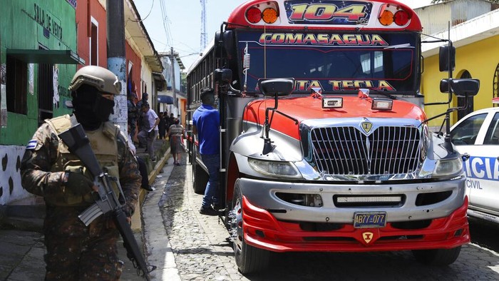 Seorang tentara berjalan di depan sebuah bus di Comasagua, El Salvador, Senin (3/10/2022).