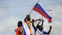 Pendukung Kapten Ibrahim Traore mengibarkan bendera Rusia saat mereka bersorak di jalan-jalan Ouagadougou, Burkina Faso, Minggu, (2/10/2022). Kepemimpinan junta baru Burkina Faso menyerukan ketenangan setelah Kedutaan Besar Prancis dan gedung-gedung lainnya diserang. AP/Kilaye Bationo