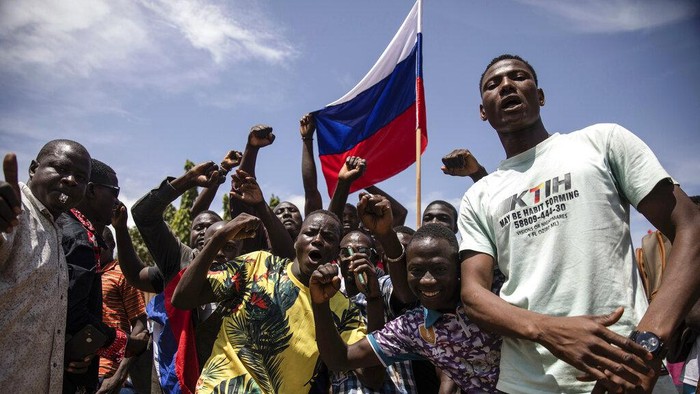 Supporters of Capt. Ibrahim Traore parade waving a Russian flag in the streets of Ouagadougou, Burkina Faso, Sunday, Oct. 2, 2022. Burkina Faso's new junta leadership is calling for calm after the French Embassy and other buildings were attacked. The unrest following the West African nation's second coup this year came after a junta statement alleged that the ousted interim president was at a French military base in Ouagadougou. France vehemently denied the claim and has urged its citizens to stay indoors amid rising anti-French sentiment in the streets. (AP Photo/Sophie Garcia)