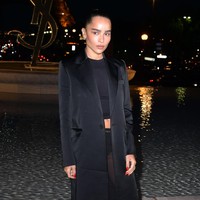 Acara Saint Laurent Womenswear Spring/Summer 2023 bertabur banyak bintang. Salah satunya yang menarik perhatian meski tampil serba hitam adalah Zoe Kravitz. Ia memadukan rok transparan dan long coat. Foto: Getty Images