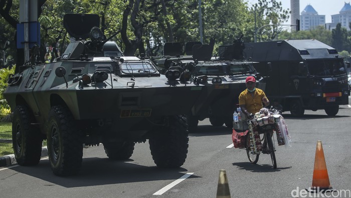 Seorang pedagang bersepeda melintasi alutsista yang dipajang jelang HUT TNI di Jalan Merdeka Utara, Jakarta, Selasa (4/10/2022).